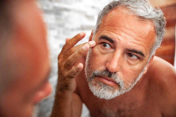 Man applying skincare while looking in a mirror